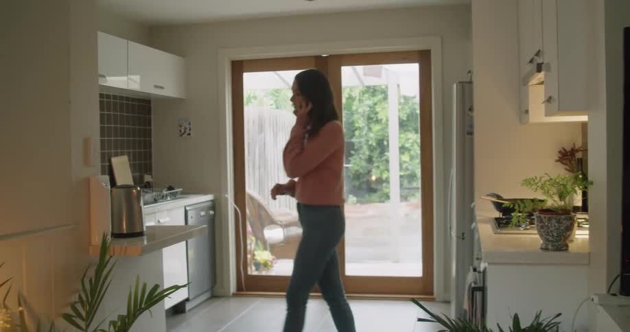 A woman is in a house talking on the phone