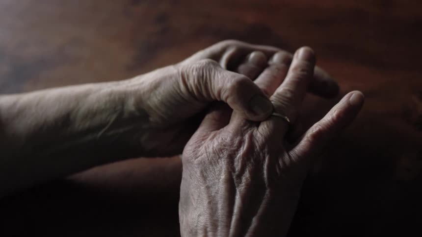 An elderly woman plays with the ring on her finger