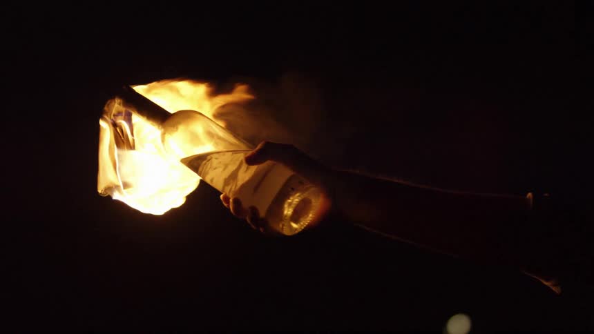 Person holding a bottle with flames as a torch