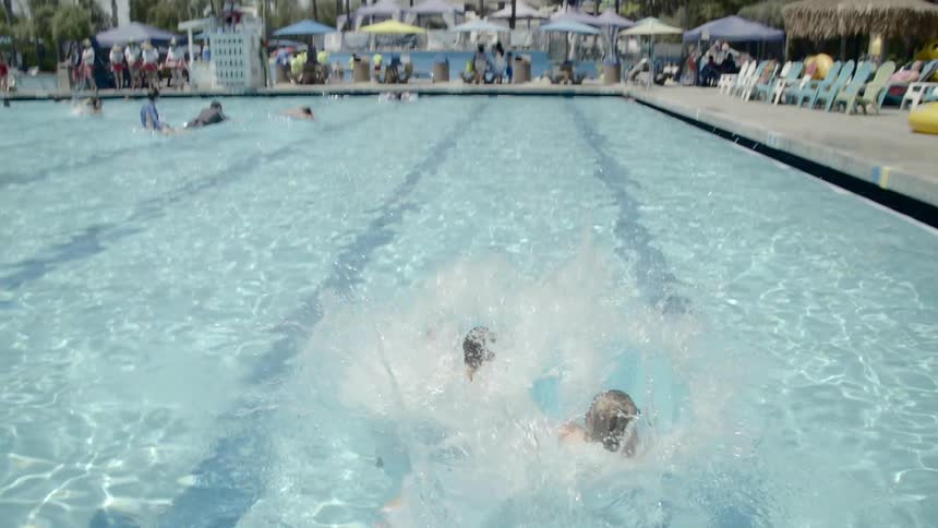 Kids are jumping in an outdoor pool