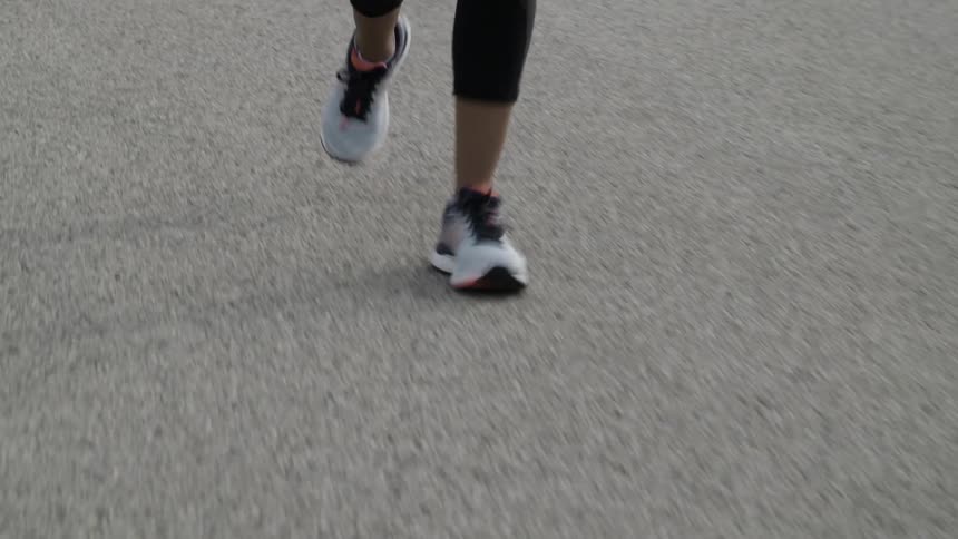 A persons feet jogging with sneakers on