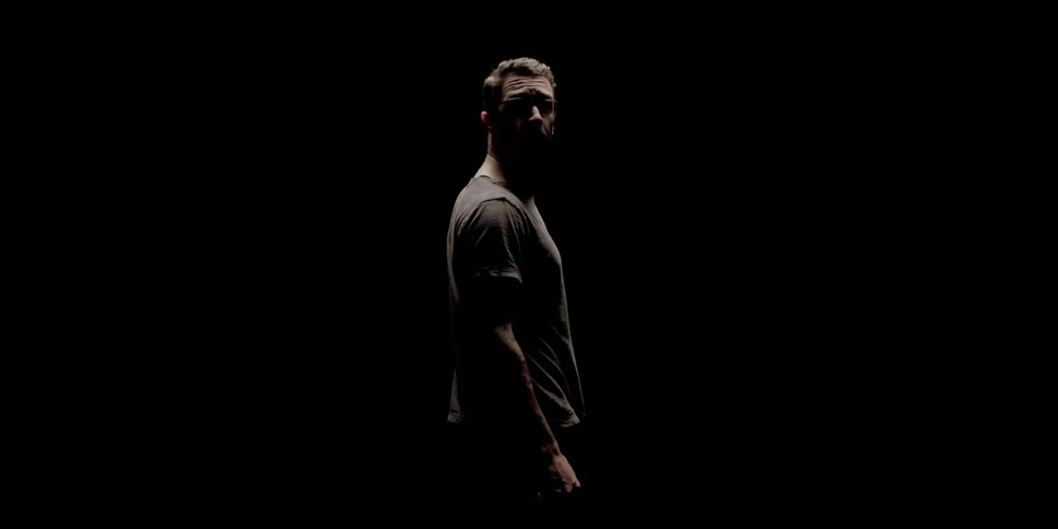 A man turning around and looking behind himself with a black background