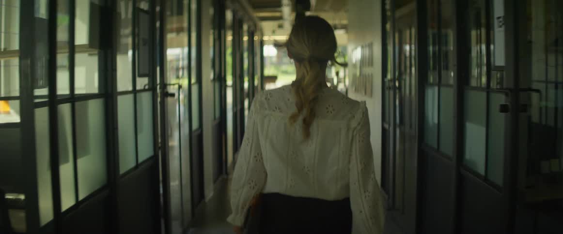 A white woman walks quickly down an office hallway