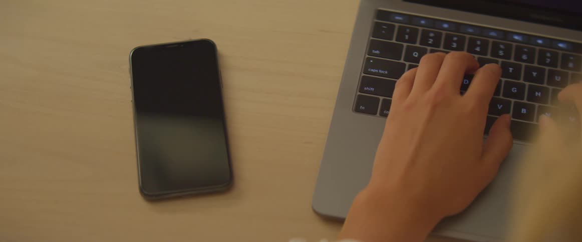 A phone call interrupts a woman as she types on a laptop