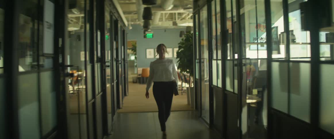 A white woman walks swiftly down an office hallway