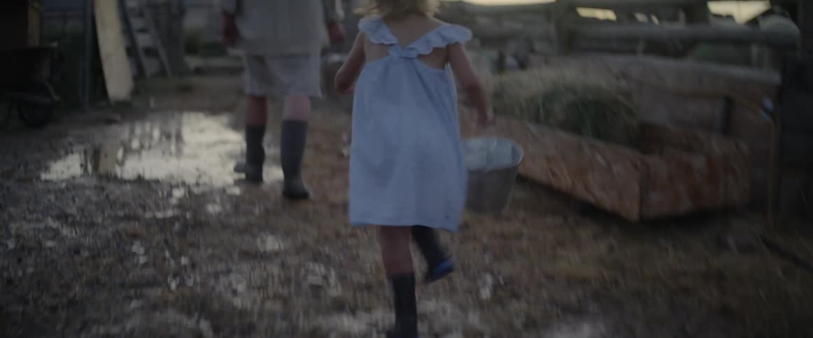 A child runs with her mother carrying a pale