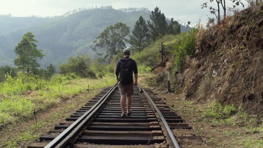 A man walks along train tracks