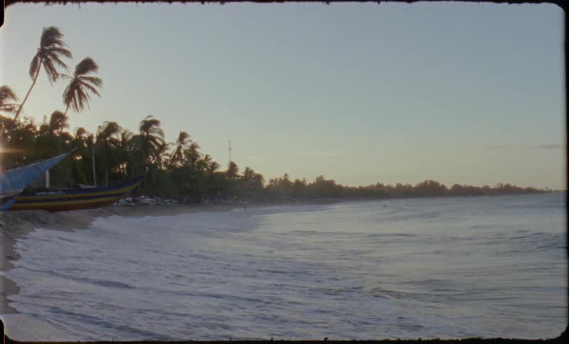 Ocean waves wash ashore a sandy beach at sunset