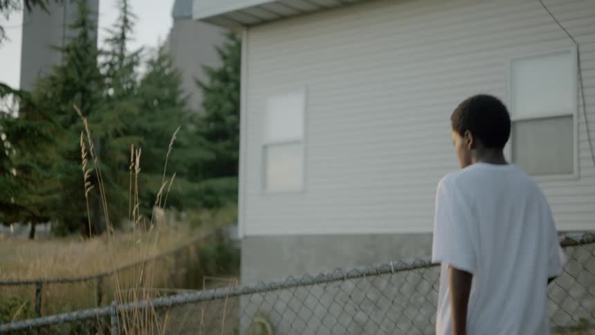A young boy walks through backyard at sunset