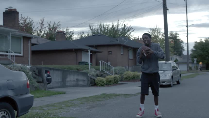 Young boys throw a football around in the street at night