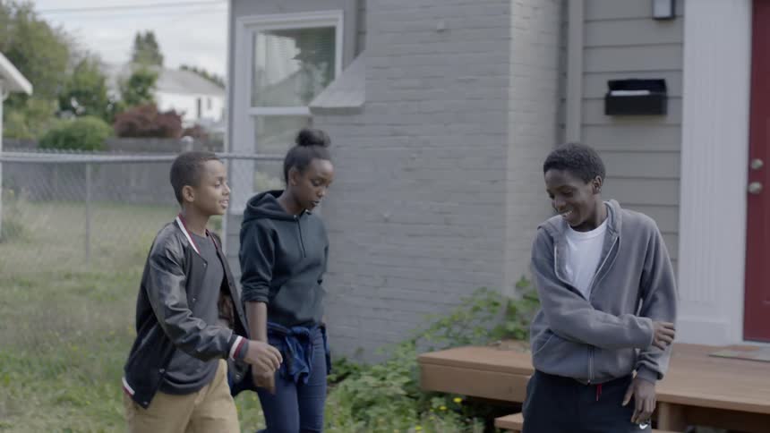 Three kids talk as they walk along a neighborhood street