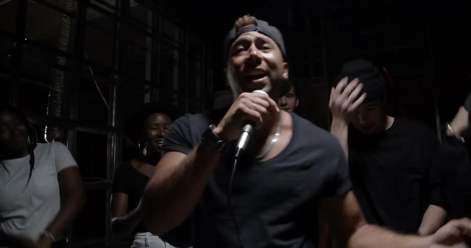 A group of people dance as a man sings