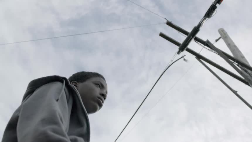A boy stands near a utility pole