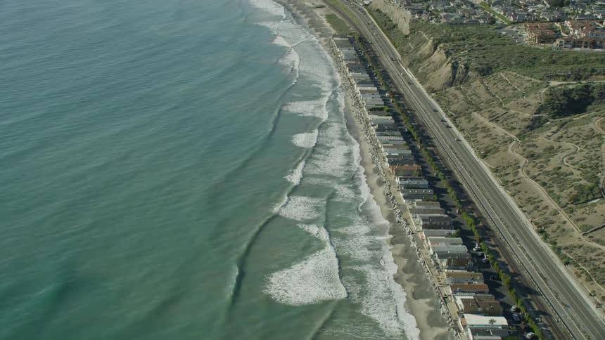 Ocean waves come to shore on a sandy beach crowded with cottages
