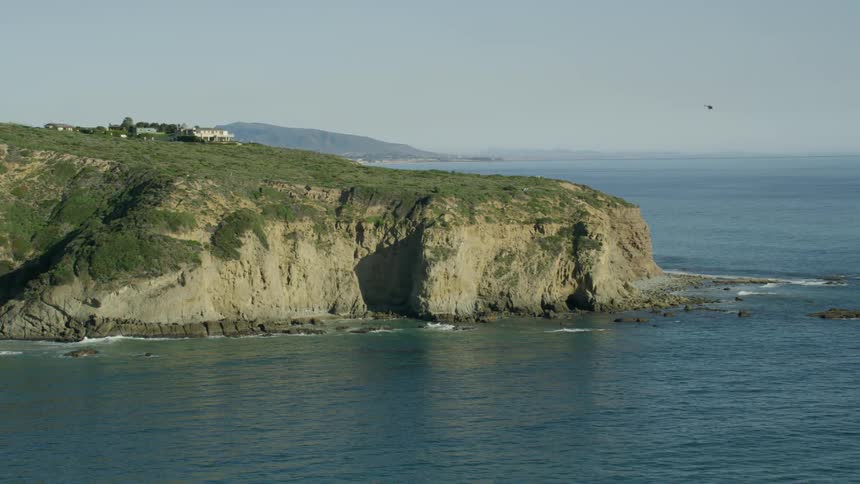 A rocky coast with the sky and a helicopter in the background