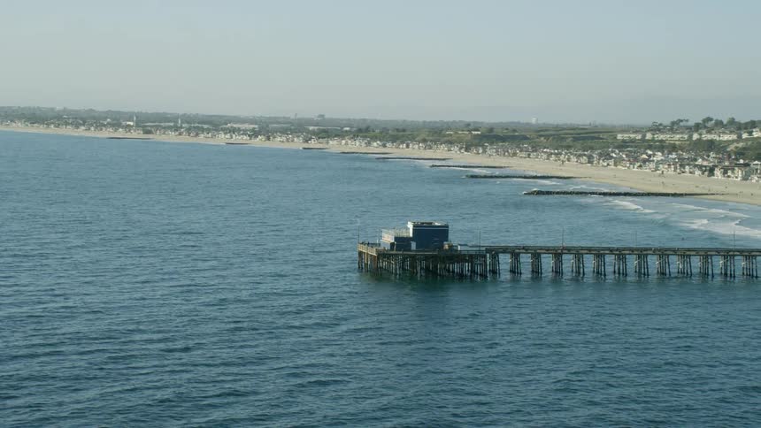 An aerial view of a pier extending into the Pacific Ocean