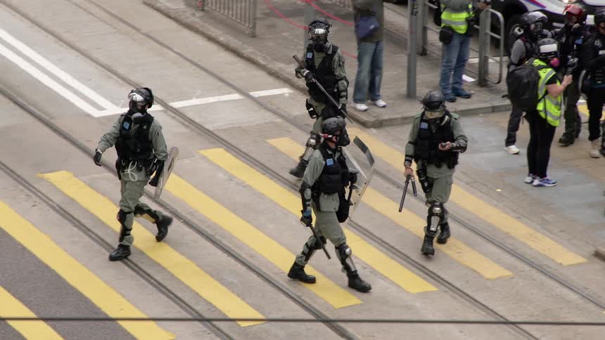 People dressed in riot gear walk onto and stand in the middle of a crosswalk