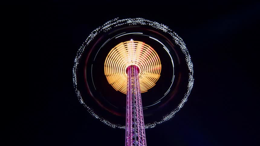 A theme park ride spins and illuminates the night sky