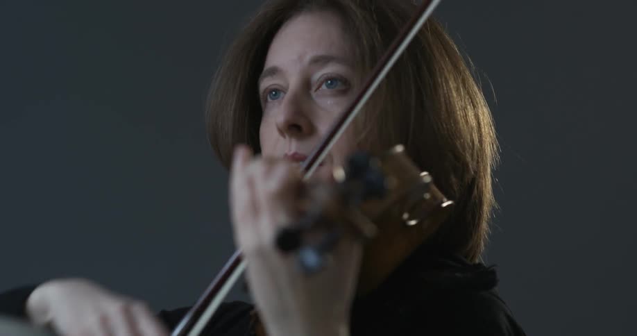 A woman is playing a violin in a room