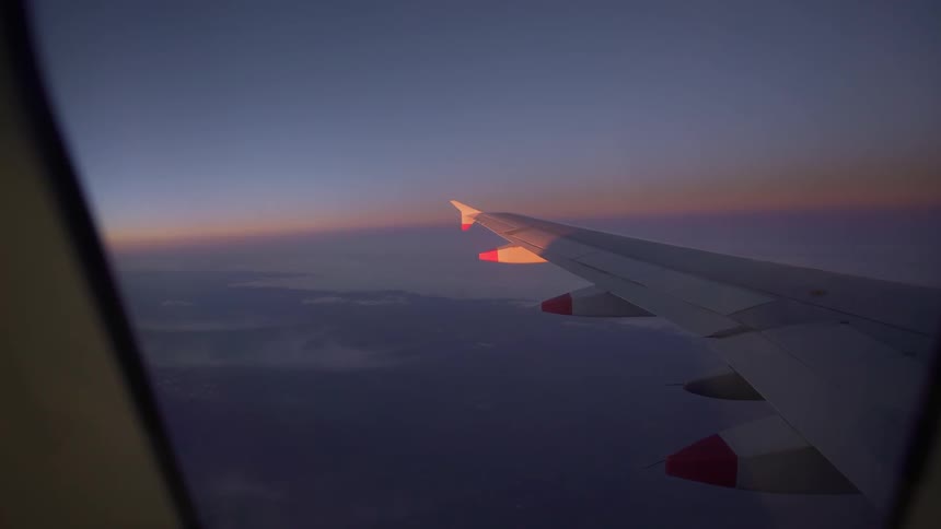 View out of a plane window of the wing as the sun sets