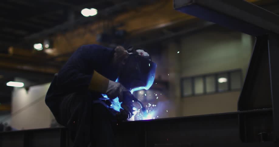A ma is welding inside a warehouse