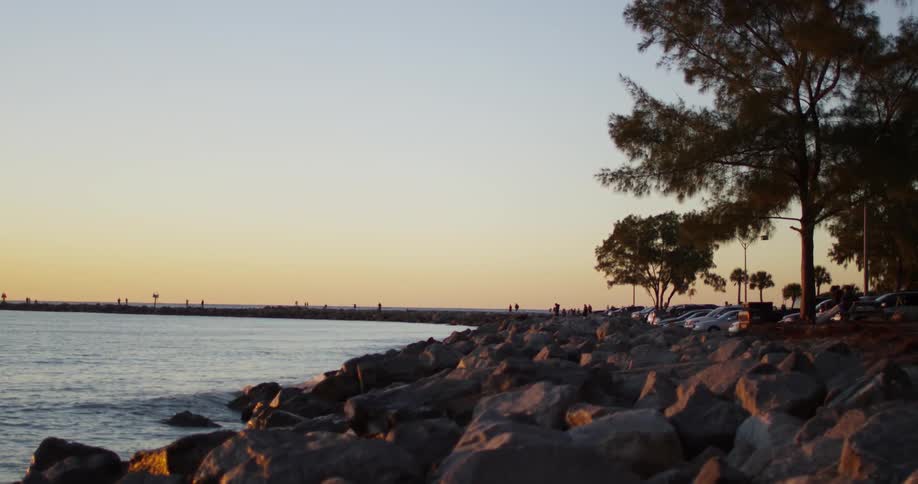 Water splashes onto a rocky beach at sunset