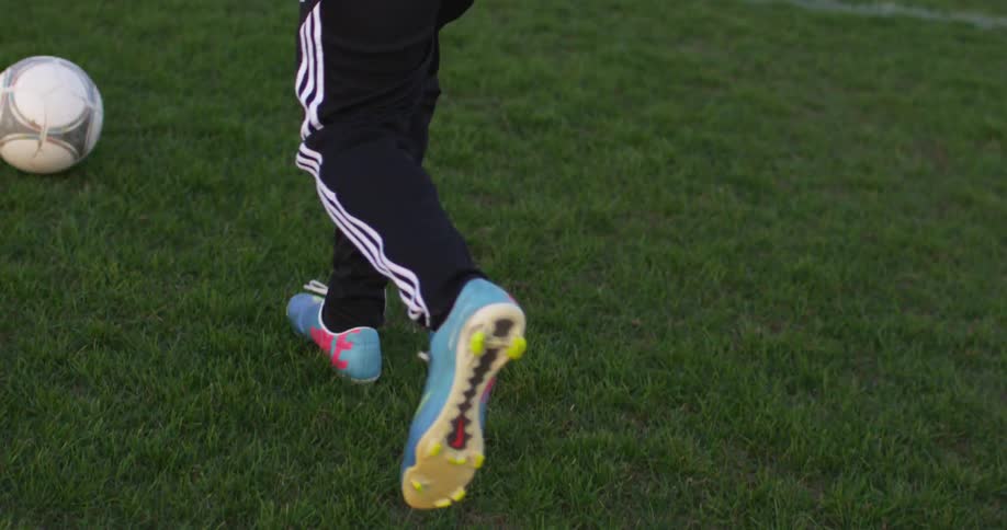 A person kicks a soccer ball before driving it towards a goal
