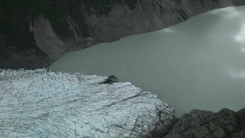 A lake at the bottom of a valley reflecting a cloudy sky