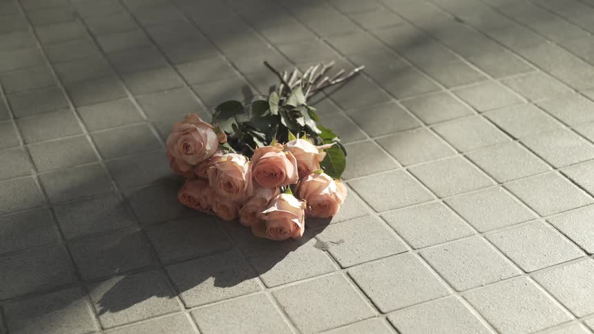 A bouquet of beige roses on cement pathway