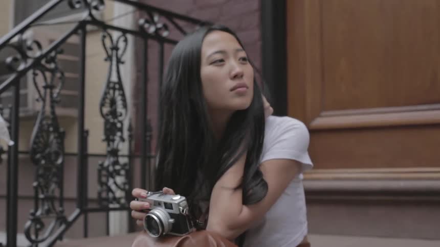 A woman is holding a camera as she sits on the steps