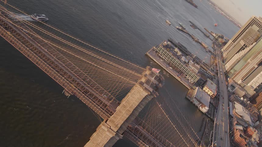 An american flag waving in the wind atop a tall support on a bridge