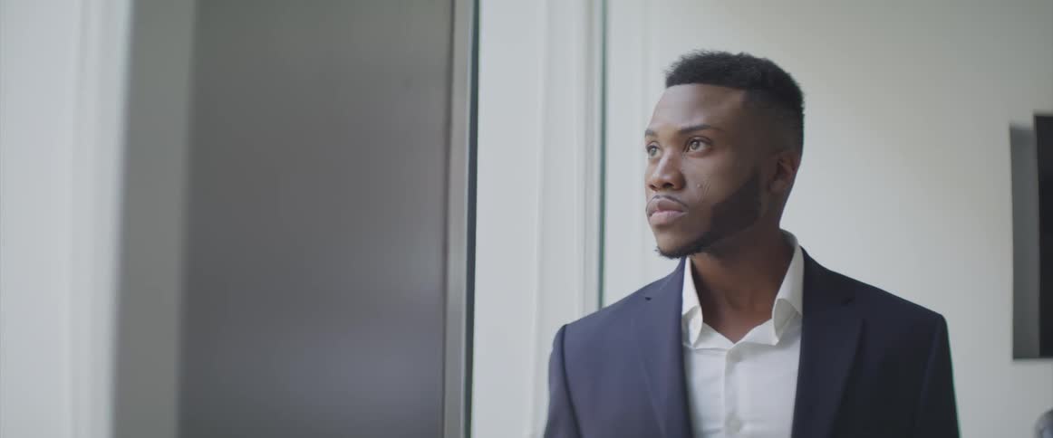 Male looking down next to a window turns his head and looks up at something outside