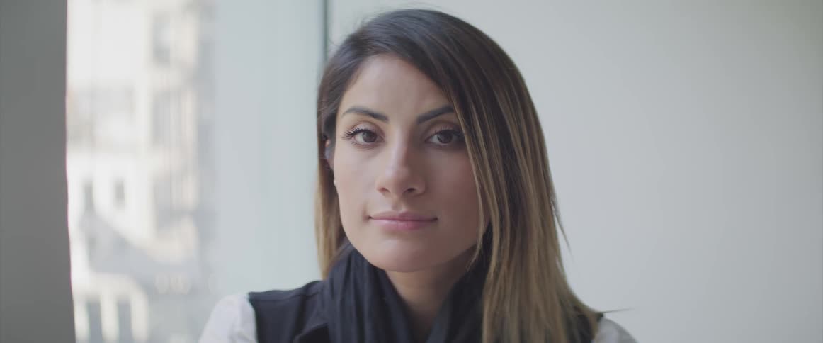A woman slowly turning her head to look into the camera