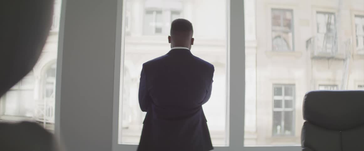 Back turned black businessman looks out the window in the office