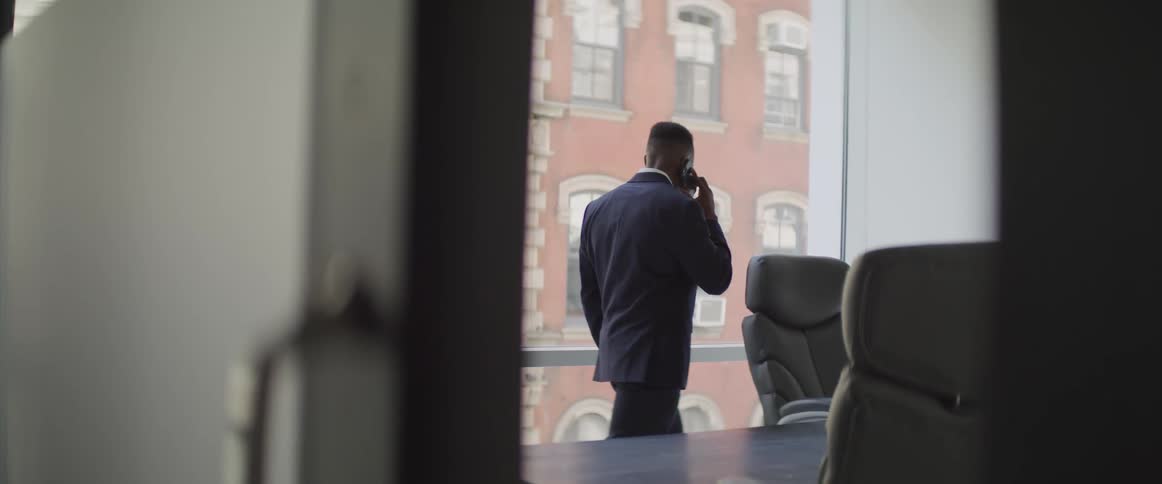 Man wearing a suit talks on smart phone while walking around the office