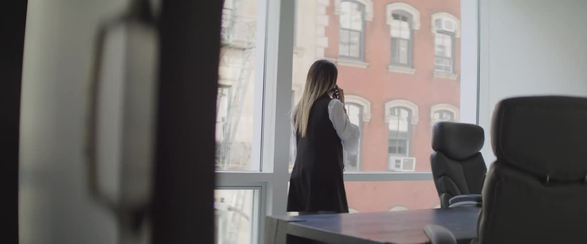 A woman walks through an office as she talks on the phone