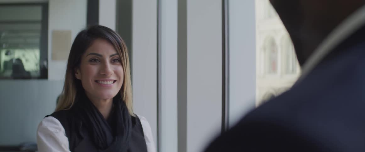 Business man and business woman shake hands and smile at each other in the office