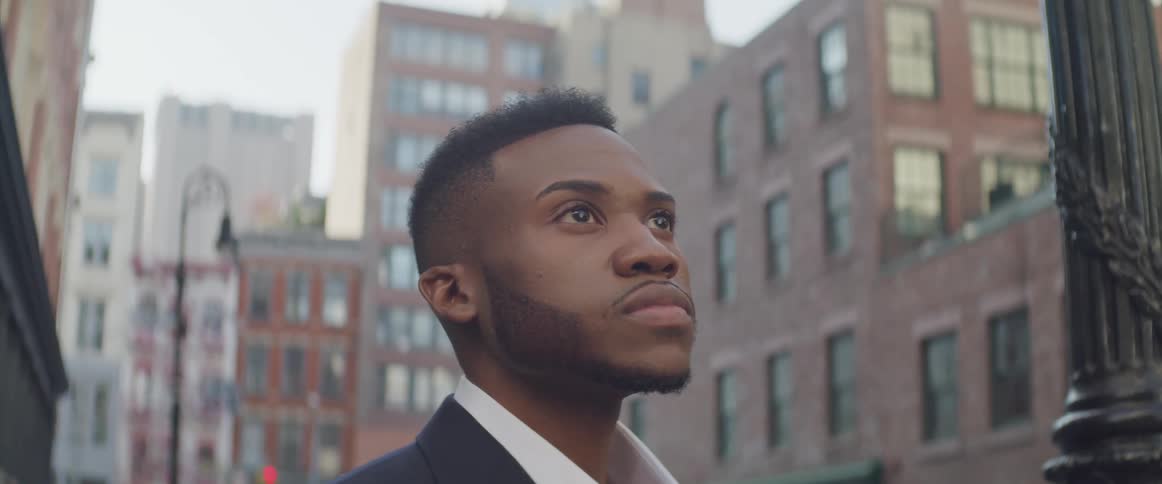 Black businessman stands and looks at the tall buildings in the city