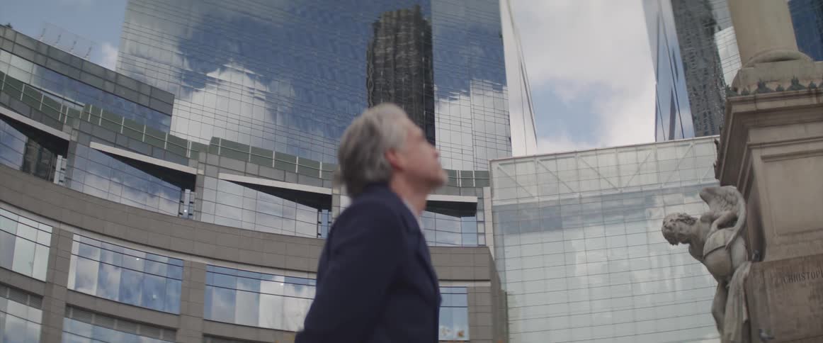 Businessman stands and looks up at the statue in front of the office building