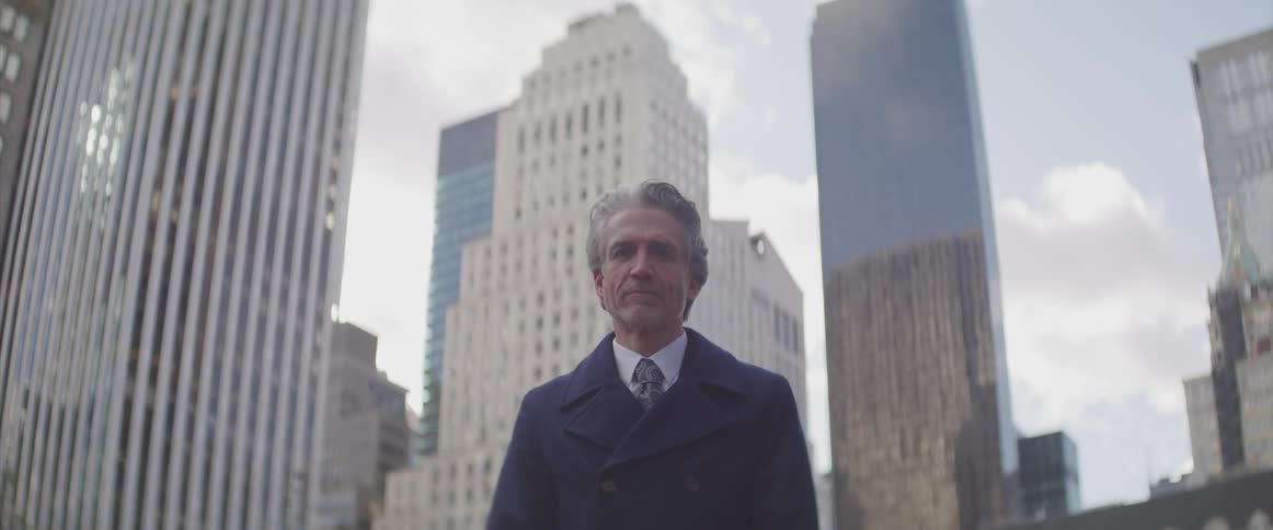 Older business man wearing an overcoat standing in the downtown of a city