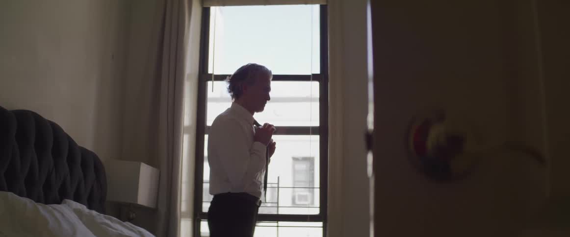 The man fixes his tie
