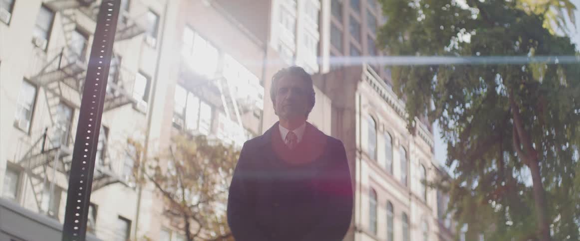 A man stands outside of a large city building