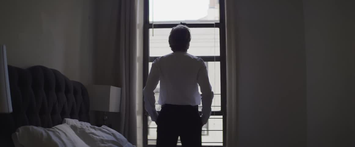 A man stands and looks out the window