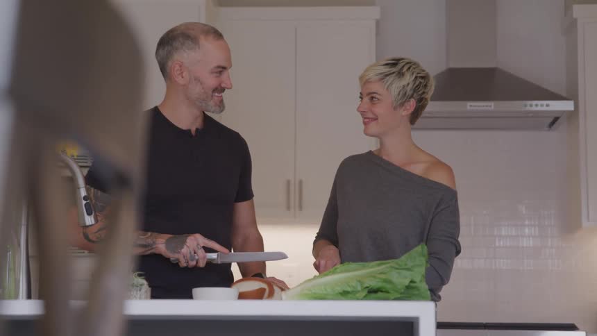 A man and woman smile at one another as they cook