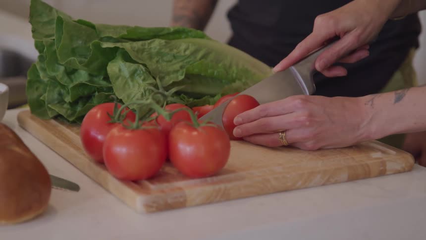 Woman cuts tomatoes with a knife on a cutting board