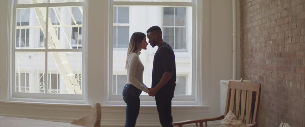 A man and woman are holding hands in a room with a brick wall