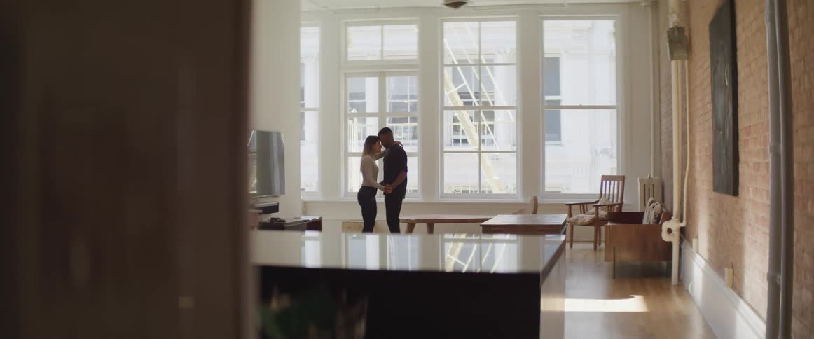 A man and woman hold each other close standing in their living room