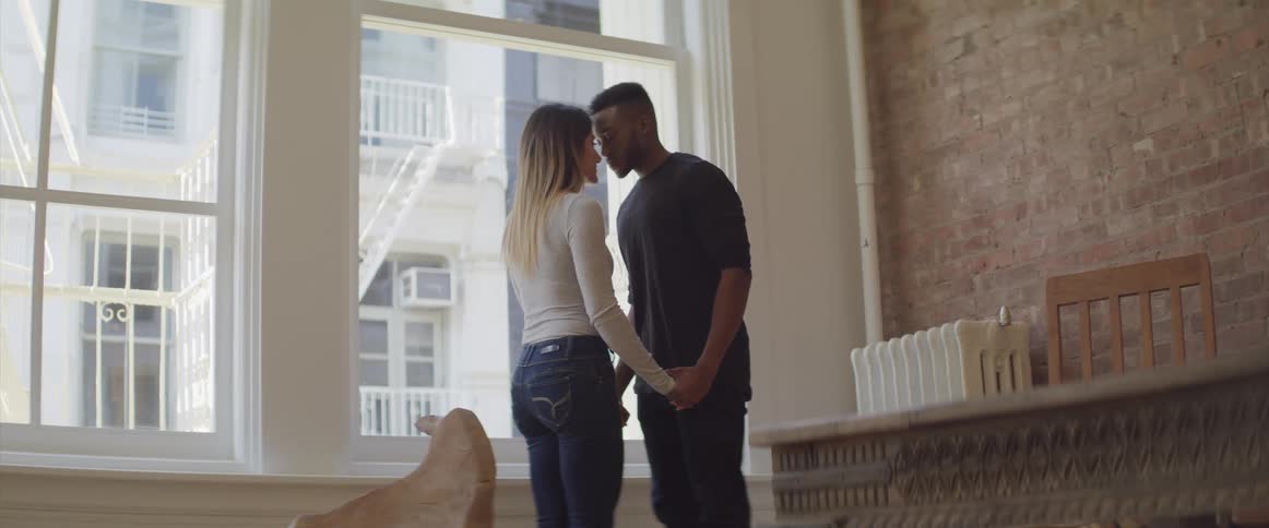 A man and woman hold each others hands standing in a living room