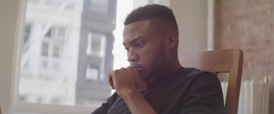 A man sits in a chair and stares blankly at a computer screen
