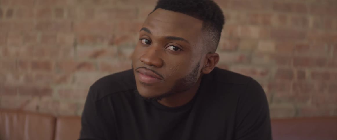 A black man turns his head while sitting on a couch